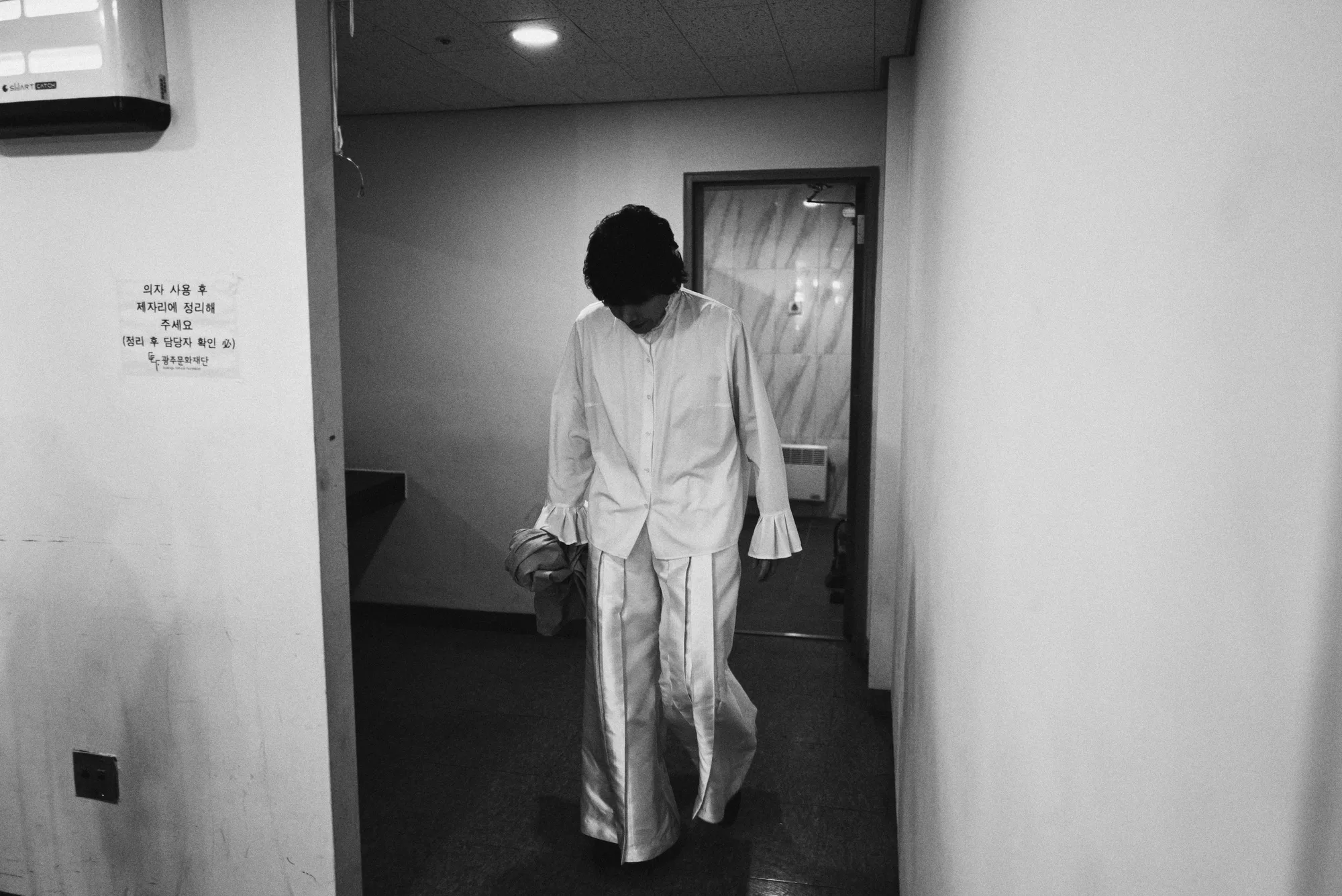 A black-and-white image of the performer singing under stage lights. Image 2.