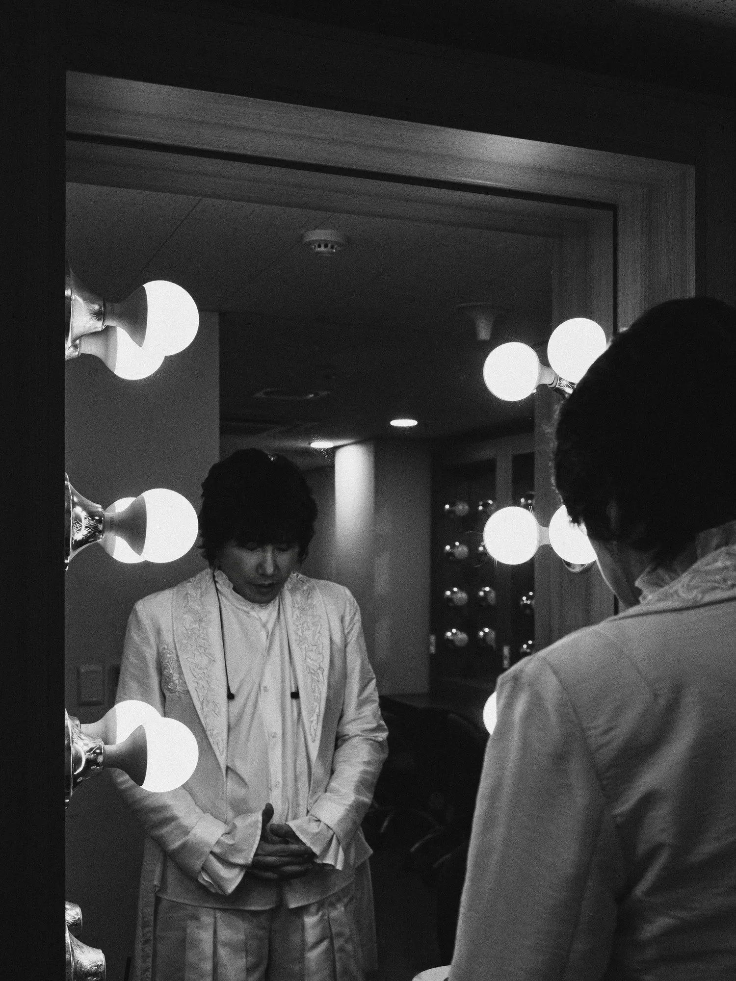 A black-and-white image of the performer singing under stage lights. Image 4.