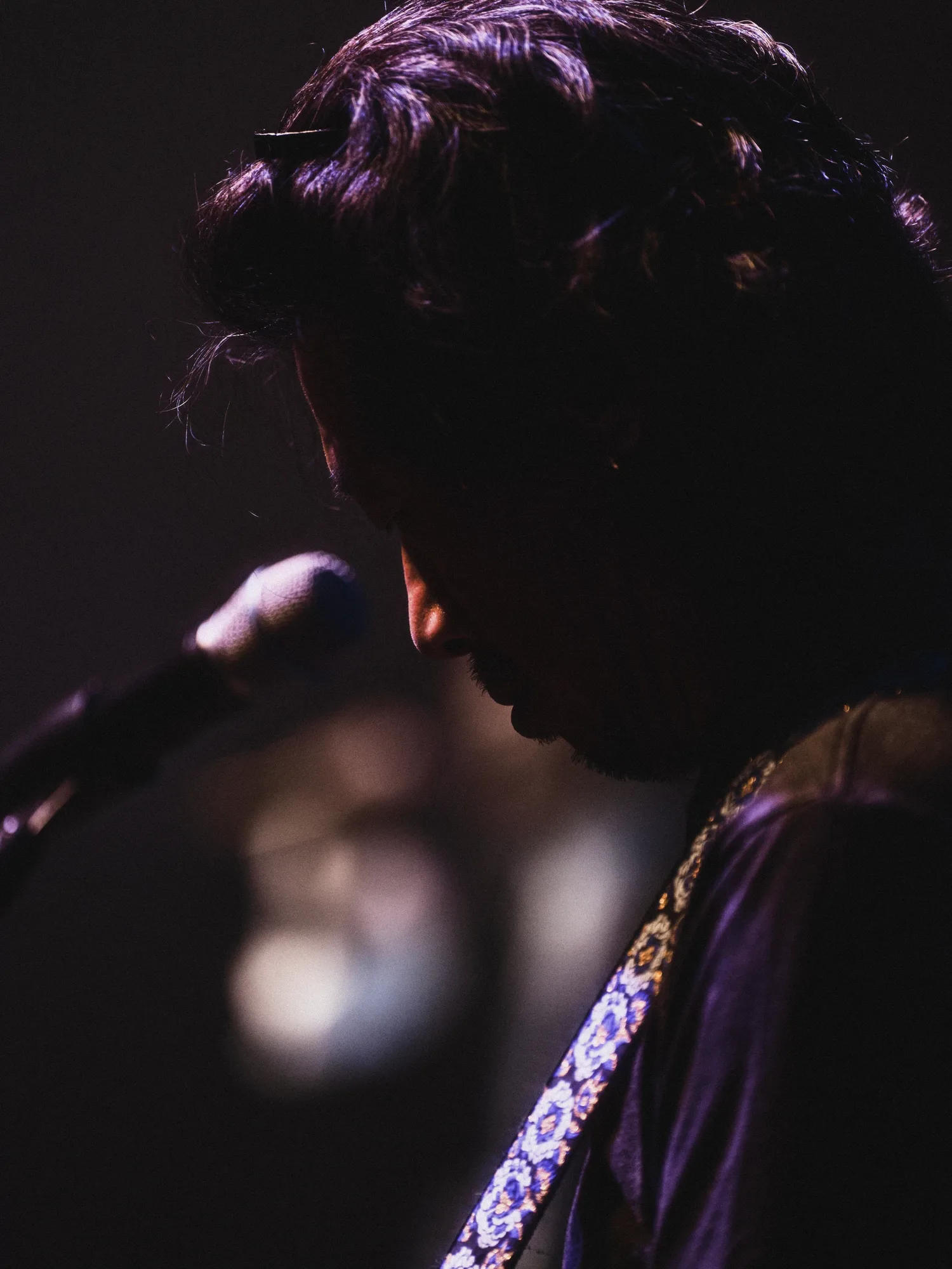 A black-and-white image of the performer singing under stage lights. Image 9.