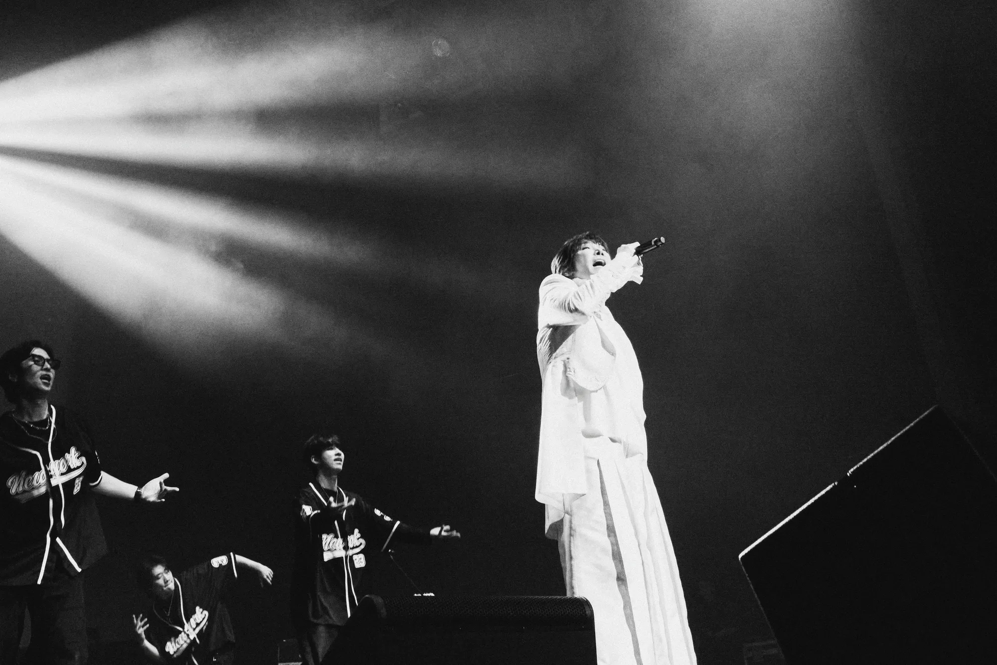 A black-and-white image of the performer singing under stage lights. Image 12.