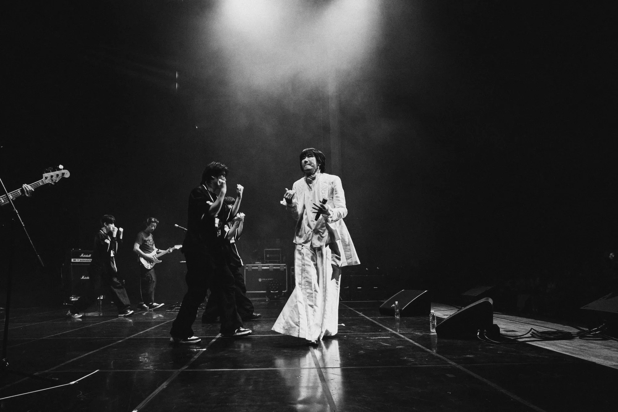 A black-and-white image of the performer singing under stage lights. Image 13.