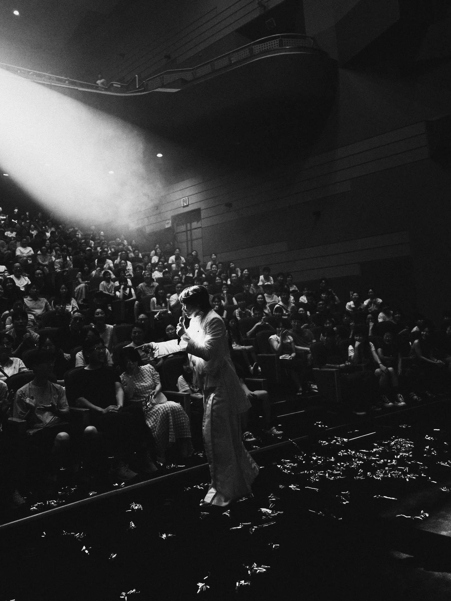 A black-and-white image of the performer singing under stage lights. Image 14.