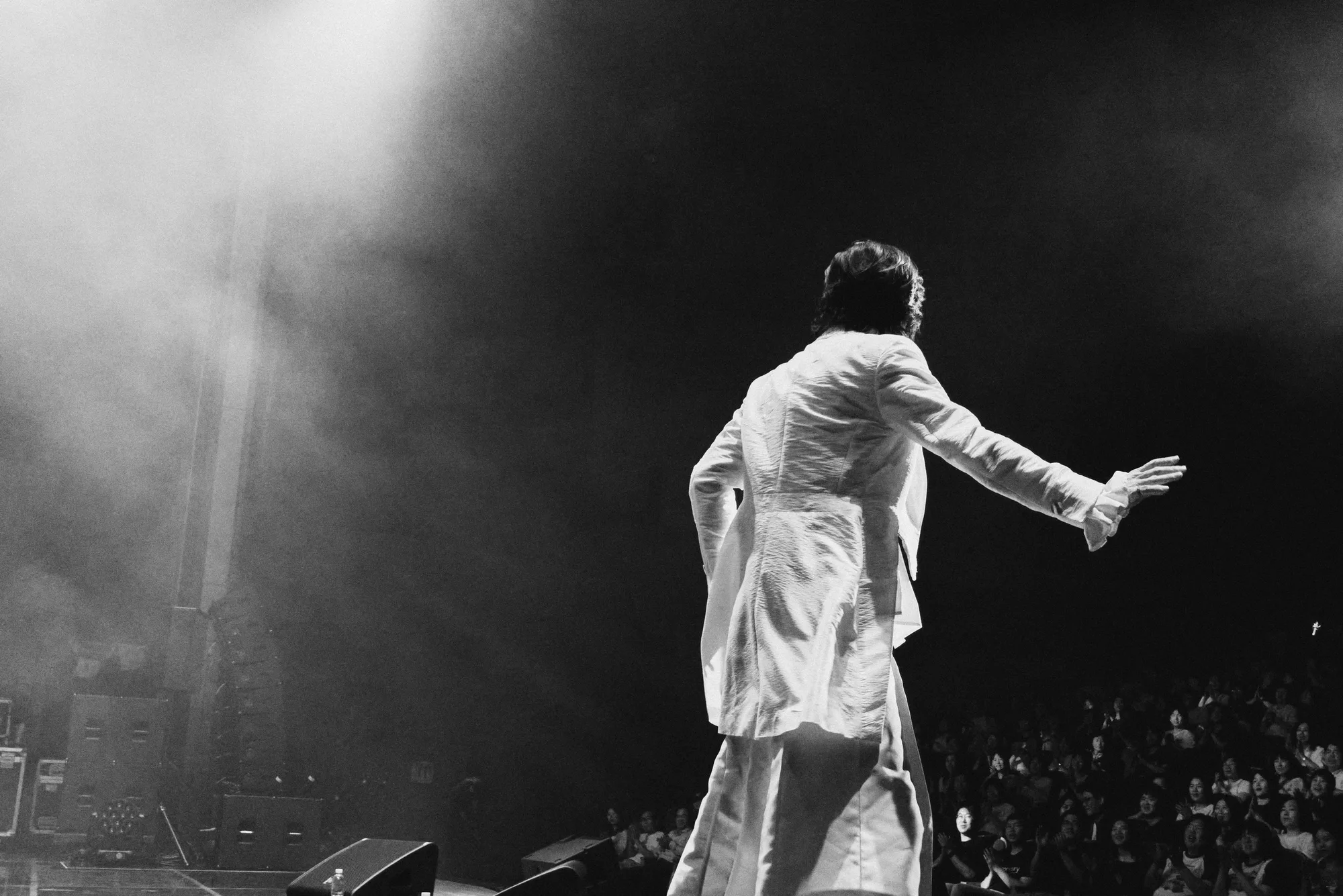 A black-and-white image of the performer singing under stage lights. Image 15.