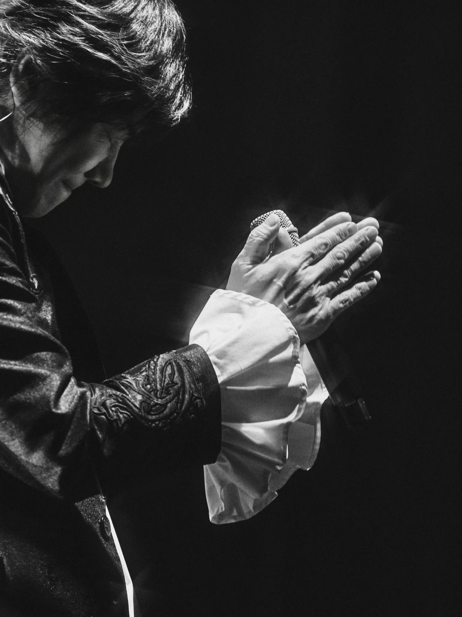 A black-and-white image of the performer singing under stage lights. Image 23.