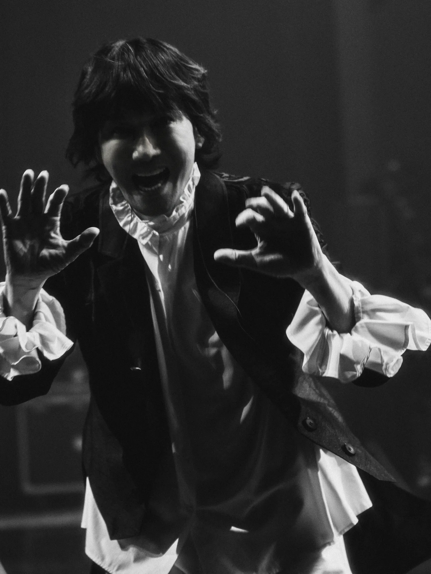 A black-and-white image of the performer singing under stage lights. Image 31.